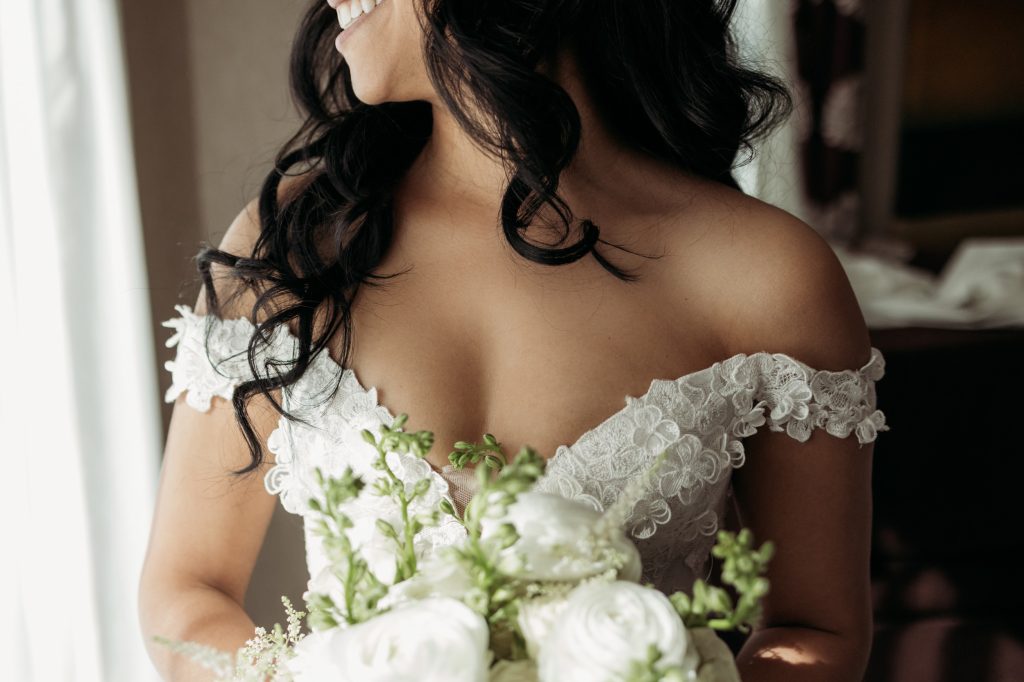 Mariée tenant son bouquet dans une robe en dentelle au style classique